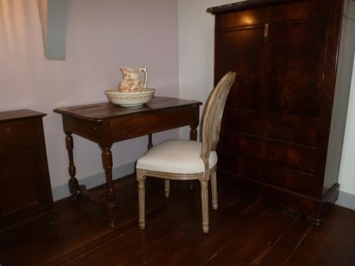 Élégant espace de travail dans la chambre du Château De Clusors avec bureau ancien en bois, fauteuil et meubles d'époque à Lilas