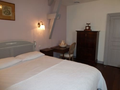 La chambre Lilas du Château De Clusors B&B à ST MENOUX, avec lit, mobilier ancien, bureau et éclairage chaleureux