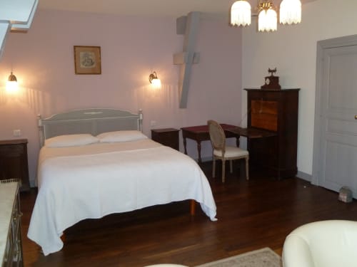 Dormitorio elegante en Château De Clusors B&B en St Menoux con cama queen, muebles de madera oscura y paredes rosa suave