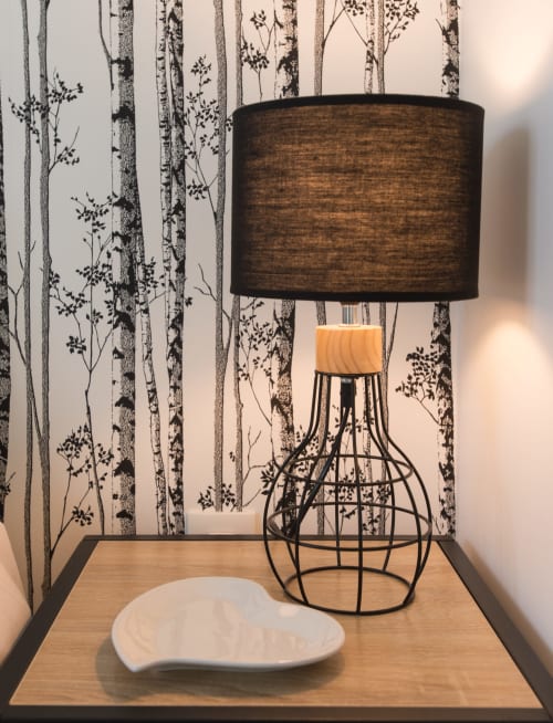 Modern lamp with wooden base and black shade beside white dish at Au Gite d'Isigny B&B in Normandy, France