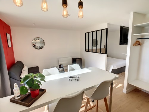 Studio moderne à la Résidence L'Hermitière avec espace repas, table blanche, vue sur le jardin et chambre visible