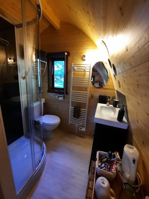 Modern glamping bathroom at Belloréade with shower, toilet, heated towel rail, and wooden finishes in Belloc, France