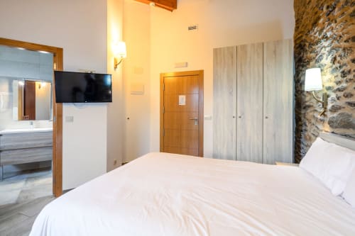 Quarto de casal moderno em O Trancallo com vista para a montanha, TV e parede de pedra em Ourense