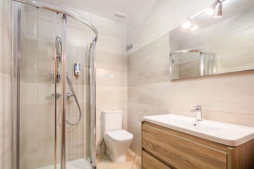 Banheiro moderno na O Trancallo B&B em Ourense com chuveiro aberto, gabinete de madeira e vaso sanitário