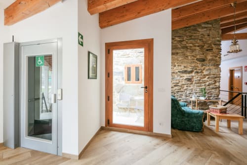 Hall d'entrée O Trancallo avec poutres en bois, ascenseur accessible et mur en pierre à Ourense, Espagne