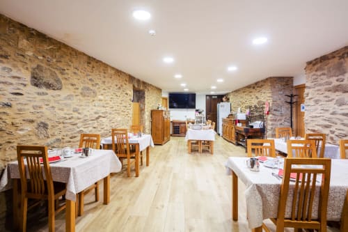 Salle à manger de la maison d'hôtes O Trancallo à Mourisca avec murs en pierre, tables en bois et décoration rustique