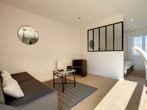 Studio moderne à la Résidence L'Hermitière avec séjour, canapé, bureau et vue sur le jardin par les fenêtres