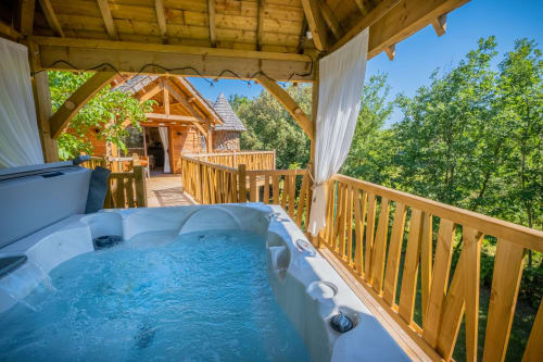 Hot tub on wooden deck overlooking forest at Domaine De Campagnac, Béquia room in Carsac-Aillac