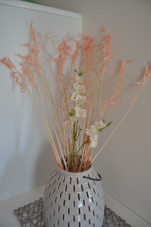 Arrangement floral décoratif avec graminées de corail séché et fleurs blanches roses dans un vase texturé blanc au Logis De La Bénétière