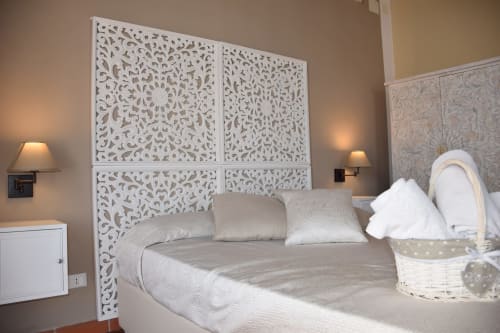 Elegante testiera bianca intagliata con cuscini decorativi nella camera Villa Blanche Holidays a Marsala, Italia