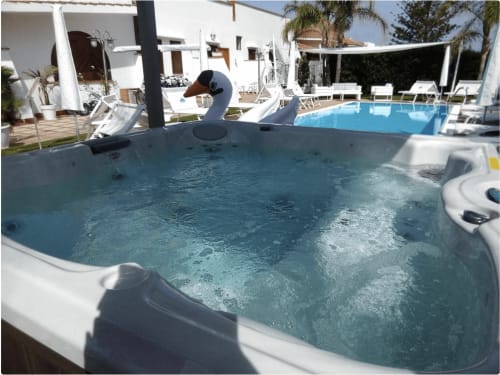 Jacuzzi con acqua frizzante a Villa Blanche Holidays a Marsala, Italia, affacciato sulla piscina e lettini bianchi