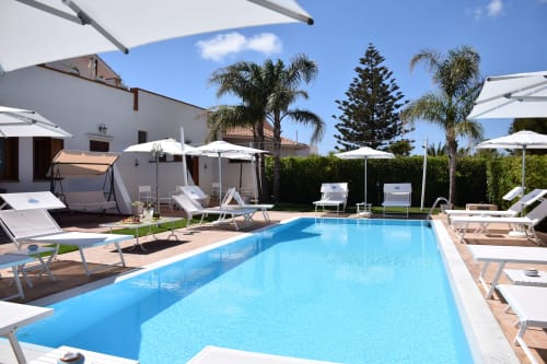 Luminosa piscina mediterranea a Villa Blanche Holidays a Marsala con lettini, ombrelloni e palme