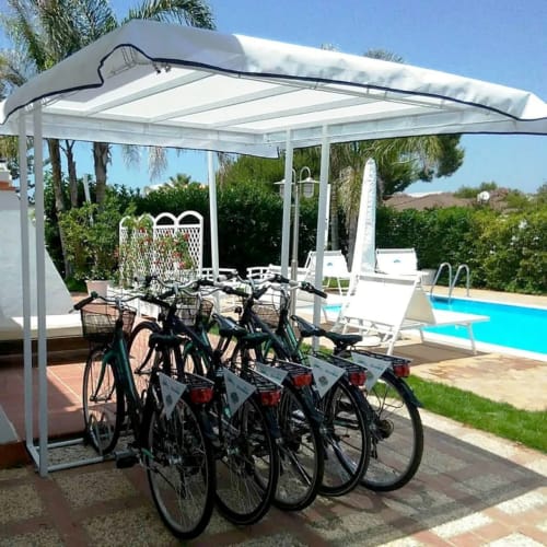 Fietsen geparkeerd onder witte pergola met zwembad en ligstoelen bij Villa Blanche Holidays in Marsala