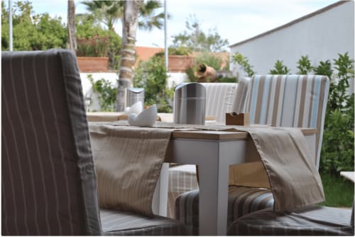 Buitenterras bij Villa Blanche Holidays met gestreepte stoelen, klein tafeltje en mediterraan tuintje in Marsala, Sicilië