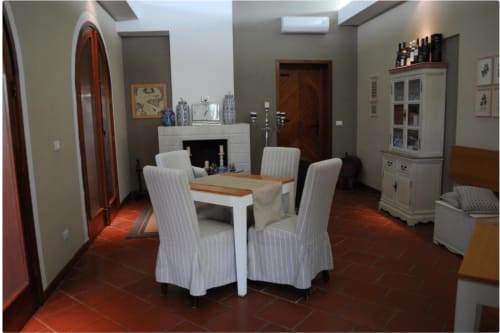 Eetkamer van Villa Blanche Holidays in Marsala met witte stoelen, houten tafel, open haard en terracotta tegels
