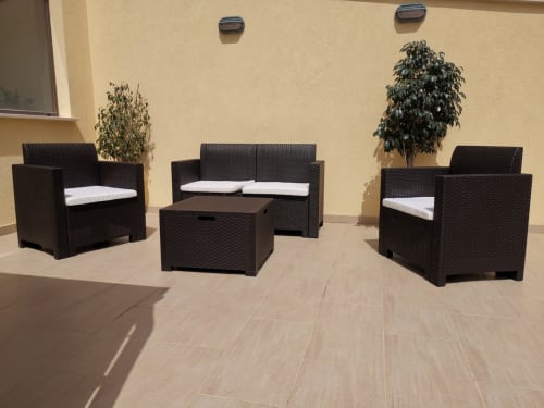 Black wicker outdoor furniture set with white cushions on a patio at Casa Vacanze Del Golfo