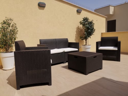Modern outdoor patio furniture set with black woven seating, white cushions, and potted plants at Casa Vacanze Del Golfo
