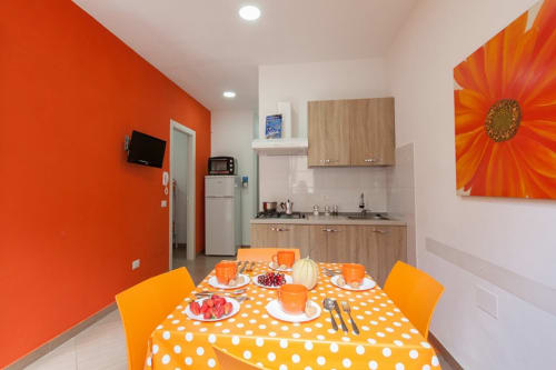 Orange apartment kitchen and dining area at Casa Vacanze Del Golfo with polka dot tablecloth and sunflower art