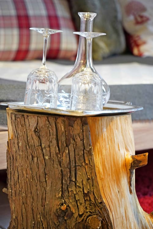 Two crystal wine glasses displayed on a wooden tree stump table at L'étape Du Fanfoué, Chamrousse mountain retreat