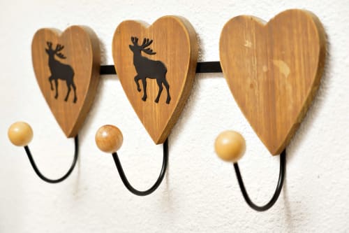 Three wooden heart-shaped wall hooks with reindeer silhouettes and wooden bead knobs in Chamrousse mountain lodge room