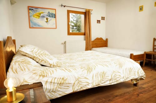 Cozy bedroom with wooden bed and golden leaf bedding at L'étape Du Fanfoué, Chamrousse mountain retreat