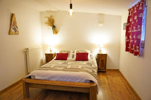 Cozy bedroom at L'étape Du Fanfoué B&B in Chamrousse with wooden bed, red accents, and warm lighting