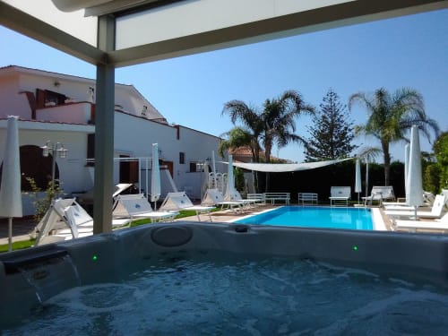 Jacuzzi e piscina di Villa Blanche Holidays a Marsala, Italia con vista giardino e palme