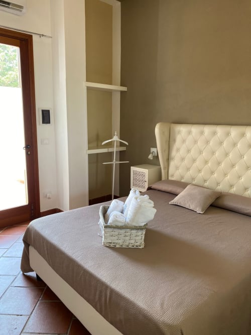 Letto trapuntato color crema con cuscini e cesto di asciugamani nella camera Mothia di Villa Blanche Holidays, Marsala