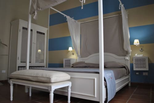 Elegante letto a baldacchino nella camera Isola Lunga di Villa Blanche Holidays, Marsala con pareti a strisce blu e arredi bianchi