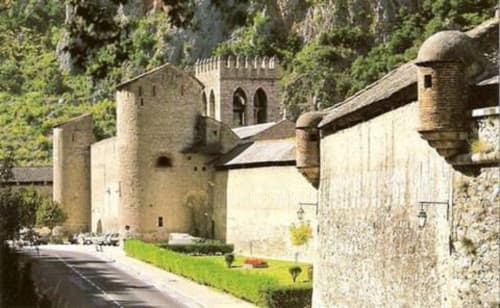 Bâtiments et tours en pierre médiévale aux Gites Mas D'en Ratéro à Thuir, entourés de verdure luxuriante