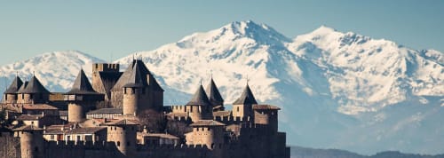 Château médiéval avec montagnes enneigées en arrière-plan, incarnant le charme accueillant de Thuir