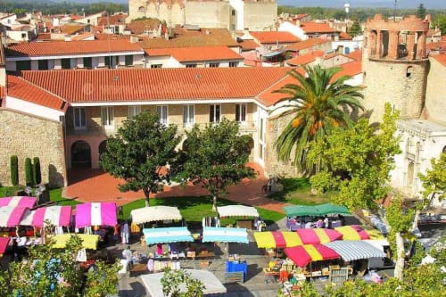 Vue aérienne des Gites Mas D'en Ratéro à Thuir, France, avec parasols colorés du marché et cour sous pierre historique