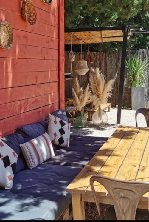 Coin salon cosy à Gites Mas D'en Ratéro à Thuir avec coussins bleus, table en bois, décoration de pampas et pierre rouge