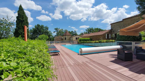 Wooden terrace and swimming pool at Domaine du Cardou with view of the cottages
