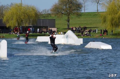 Wakeboarder effectuant des figures sur le lac aux Forges Du Lou près de Jugon-les-Lacs avec des spectateurs