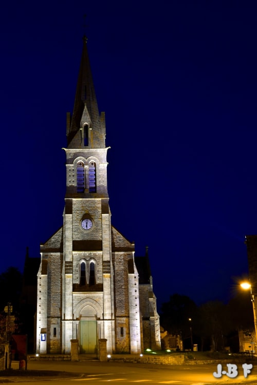 Église en pierre historique illuminée la nuit à Jugon-les-Lacs, près du gîte Les Forges Du Lou