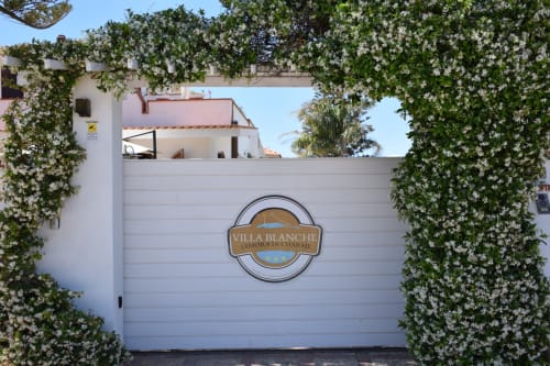 Cancello d'ingresso di Villa Blanche Holidays con rampicanti bianchi in fiore a Marsala, Italia