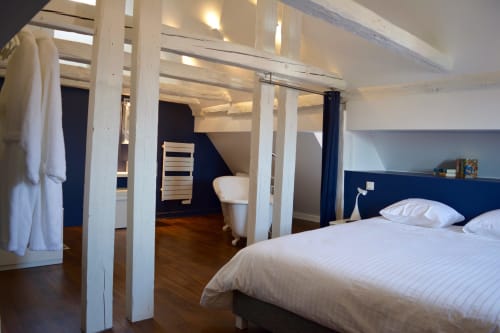 Camera da letto in stile loft moderno con colonne bianche, testata blu scuro e pavimenti in legno presso Reflets Sur La Lauch a Colmar