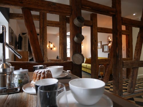 科尔马公寓内的乡村餐厅，配有木梁、白色餐具和河景