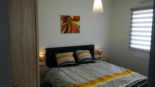 Chambre moderne à la Résidence des dunes à Landéda avec lit queen, linge de lit à motifs, œuvres d'art colorées et style contemporain