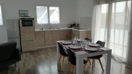Cuisine-séjour moderne de la Résidence des dunes B&B à Landéda avec meubles bois, table îlot grise et vue mer