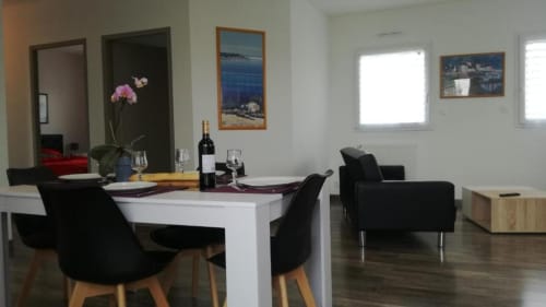 Salle à manger moderne de la Résidence des dunes BnB à Landéda : table blanche, chaises noires, bouteille de vin et art côtier