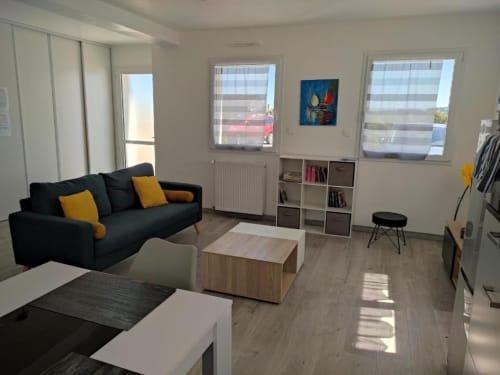 Studio moderne à la Résidence des dunes à Landéda avec canapé noir, table en bois et grandes fenêtres sur