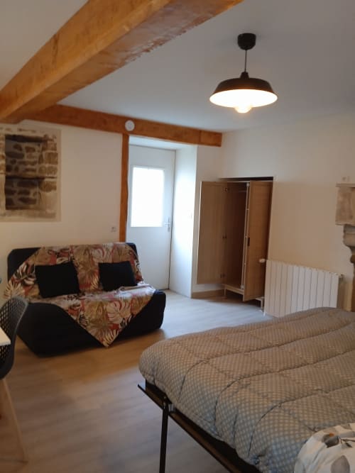 Spacieuse chambre quatre lits aux Clématites en Cotentin avec lit, canapé, poutres en bois et équipements modernes à Saint-Floxel.