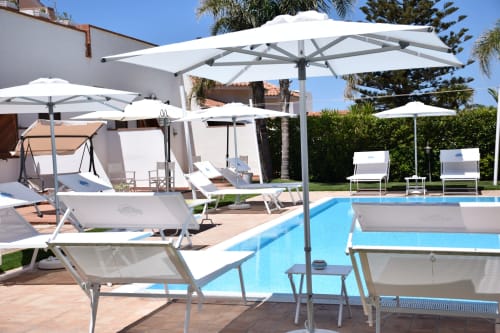 Area piscina Villa Blanche Holidays a Marsala con lettini, ombrelloni bianchi e vista sul giardino
