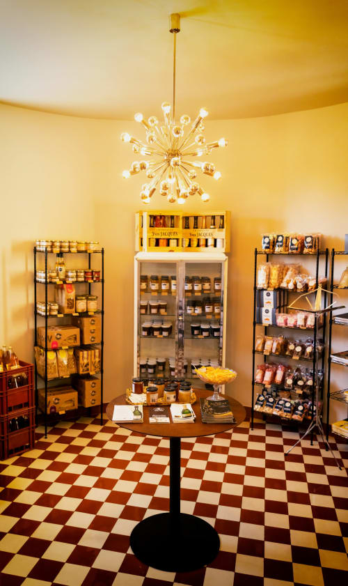 Luxury gourmet shop at Le Petit Château in Baye featuring gold starburst chandelier and shelves of Yves Jacques products