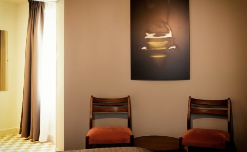 Two wooden chairs with orange cushions in Le Petit Château guest room, Baye, with glowing wall art