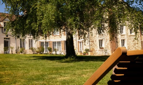 Le Petit Château B&B in Baye, France: manicured lawn with ivy-covered trees and elegant brick buildings