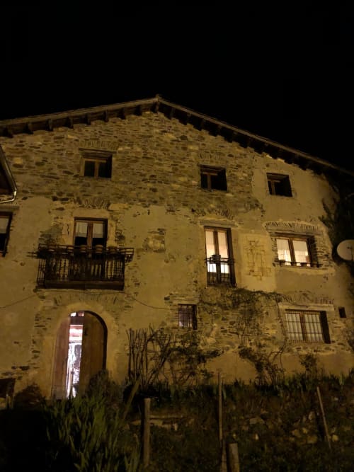 Casa Tapiolas histórica de piedra en Molló, Girona, exterior nocturno con ventanas iluminadas
