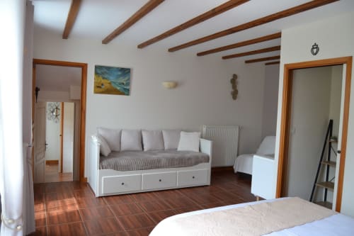 Chambre spacieuse du Logis De La Bénétière avec poutres apparentes, lit de repos et vue sur le jardin à Treize-Vents
